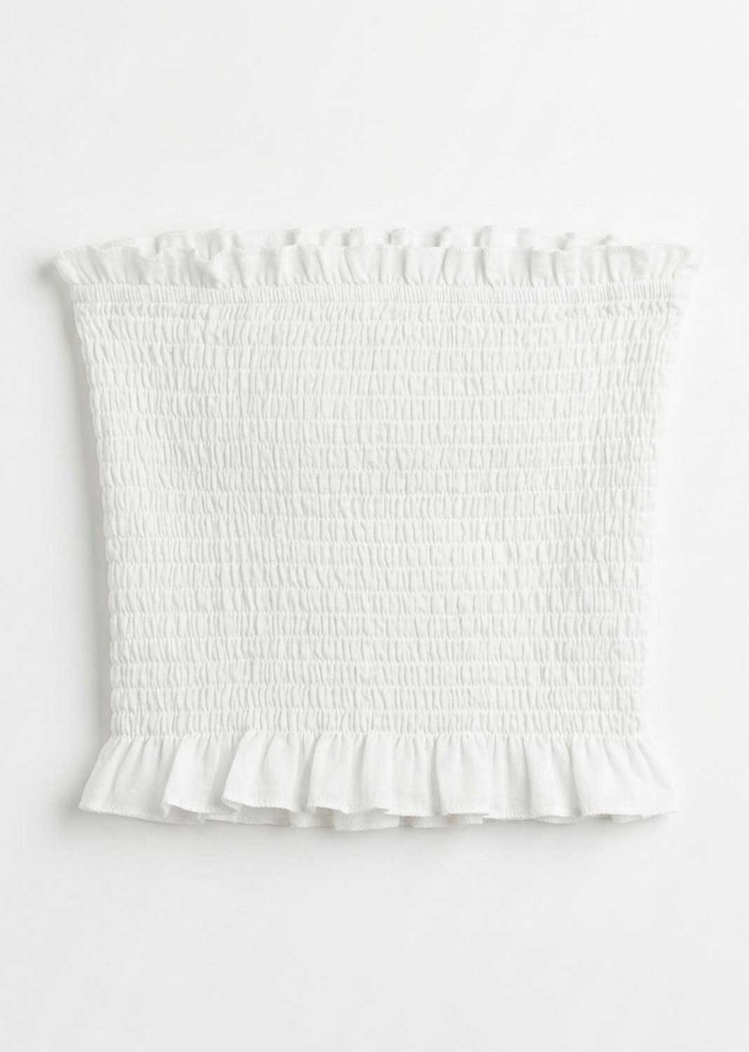 White smocked tube top with ruffled trim at the neckline and hem, shown flat against a white background.