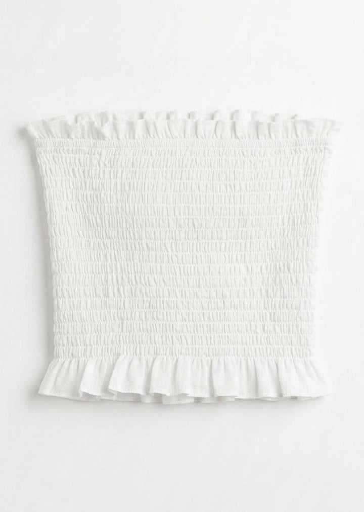 White smocked tube top with ruffled trim at the neckline and hem, shown flat against a white background.