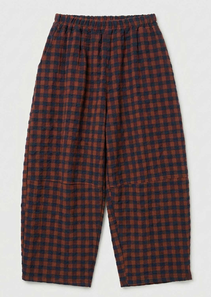 A pair of loose-fitting cropped pants with an elastic waistband, featuring a red and navy blue checkered plaid pattern, shown against a plain light gray background.
